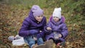 Two sisters drink cocoa with marshmallows in the autumn park