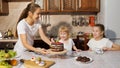 Two sisters drink tea with sweets and talk whle their mother brings cake. Royalty Free Stock Photo