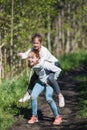 Two sisters girls friends teenagers riding each other having fun in the Park.