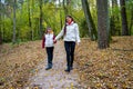 Two sisters holding hands, dressed in light jackets, walking in the park in autumn Royalty Free Stock Photo