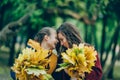 Two sisters hug, with a bunch of leaves in the park. Royalty Free Stock Photo