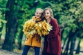 Two sisters hug, with a bunch of leaves in the park. Royalty Free Stock Photo