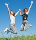 Two sisters in jeans jumping outdoors