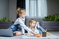 Two sisters lying on the floor at living room using laptop, playing and drawing Royalty Free Stock Photo