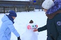 Two sisters make snowman in winter day