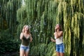 Two sisters, making blowing soap bubbles in park in summer. Young pretty girls, wearing jeans shorts and green beige tops, having Royalty Free Stock Photo
