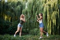 Two sisters, making blowing soap bubbles in park in summer. Young pretty girls, wearing jeans shorts and green beige tops, having Royalty Free Stock Photo