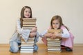 Two sisters with a pile of books on the floor in the room. The concept of education and development of children. Love of Royalty Free Stock Photo