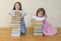 Two sisters with a pile of books on the floor in the room. The concept of education and development of children. Love of Royalty Free Stock Photo