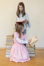 Two sisters with a pile of books on the floor in the room. The concept of education and development of children. Love of