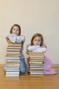 Two sisters with a pile of books on the floor in the room. The concept of education and development of children. Love of Royalty Free Stock Photo