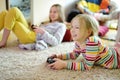 Two sisters playing video games at home. Children having fun together holding gaming controllers. Family leisure and fun