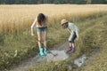 Two sisters in rain boots playing in puddle of rainwater Royalty Free Stock Photo