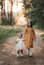 Two sisters run through the forest holding hands. Summer sunny day and girls in light dresses Royalty Free Stock Photo