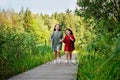 Two sisters run on a wooden deck in the city park in the open air. Freedom and carelessness. Happy childhood