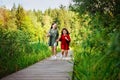 Two sisters run on a wooden deck in the city park in the open air. Freedom and carelessness. Happy childhood