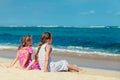 Two sisters sitting on the beach and look at the ocean
