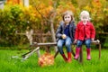 Two sisters sitting on a bench on autumn day