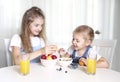 Two sisters sitting at kitchen table eating fruits.Healthy nutrition concept.Vitamin food.Children have a lunch.Frendship Royalty Free Stock Photo