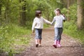 Two sisters walking on path holding hands smiling