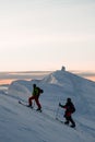 two skiers climb up to the top of a snowy mountain slope