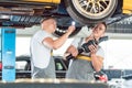 Two auto mechanics analyzing the rims of a lifted car Royalty Free Stock Photo