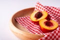 Two slice of peach nectarine fruit with seed in wooden plate with red checkered tablecloth on white background Royalty Free Stock Photo