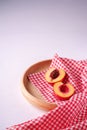 Two slice of peach nectarine fruit with seed in wooden plate with red checkered tablecloth on white background Royalty Free Stock Photo