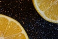 Two sliced yellow lemons on a shimmering dark background. Ingredient for party cocktails and other drinks. Glowing bokeh of stars