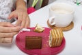 Two slices of honey cake. One of them is with chocolate. A woman eats dessert for Breakfast. Next to it is a Cup of tea with milk Royalty Free Stock Photo