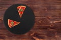 Two slices of hot pizza with spicy salami, arugula, cherry tomatoes, mushrooms and texas spice mix, on a slate black platter Royalty Free Stock Photo