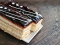 Two slices of layered cake with butter cream and chocolate icing on wooden table Royalty Free Stock Photo