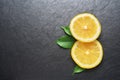 Two slices of lemons with leaves on black slate background Royalty Free Stock Photo