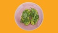 Two slices of mashed avocado toast garnished with fresh rocket or arugula salad set on a pink plate against an orange background Royalty Free Stock Photo