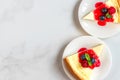 Two slices of New York cheesecake in plates with fresh berries, jam and mint on white marble table. top view Royalty Free Stock Photo