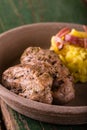 Two slices of pork tenderloin on clay plate with potatoes