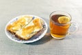 Two slices of white bread with butter and jam on a plate. Cup of tea with limon. Bright background.Breakfast Royalty Free Stock Photo