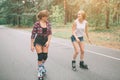 Two slim and young women and roller skates. One female has an inline skates and the other has a quad skates. Girls Royalty Free Stock Photo