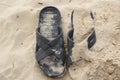 Two Slippers in the sand half in the frame