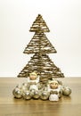Two small angels stand in front of Christmas tree with silver balls