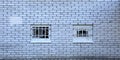 Two small barred windows in a white brick wall Royalty Free Stock Photo