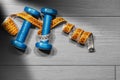Tape measure and blue dumbbells on gym floor Royalty Free Stock Photo