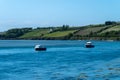 Two small boats are anchored in Clonakilty Bay on a sunny spring day. Beautiful Irish seaside landscape. Clear sky and blue water