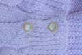 Two small brown plastic buttons on the violet woolen fabric