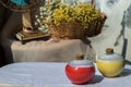 Two small ceramic vases on white textured table cloth in front of Bouquet of flowers in woven basket and Vintage fan Royalty Free Stock Photo