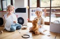 Two small children with doctor uniforms indoors at home, playing.