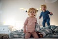 Two small children jumping on bed indoors at home, having fun. Royalty Free Stock Photo