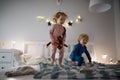 Two small children jumping on bed indoors at home, having fun. Royalty Free Stock Photo