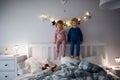 Two small children playing on bed indoors at home, having fun. Royalty Free Stock Photo