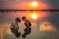 Two small children playing on the seashore during sunset